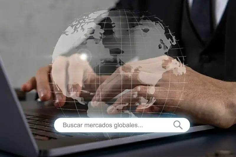 Empresario utilizando un portátil con una interfaz de búsqueda que dice "Buscar mercados globales" y un holograma del mundo, representando la estrategia de SEO internacional.